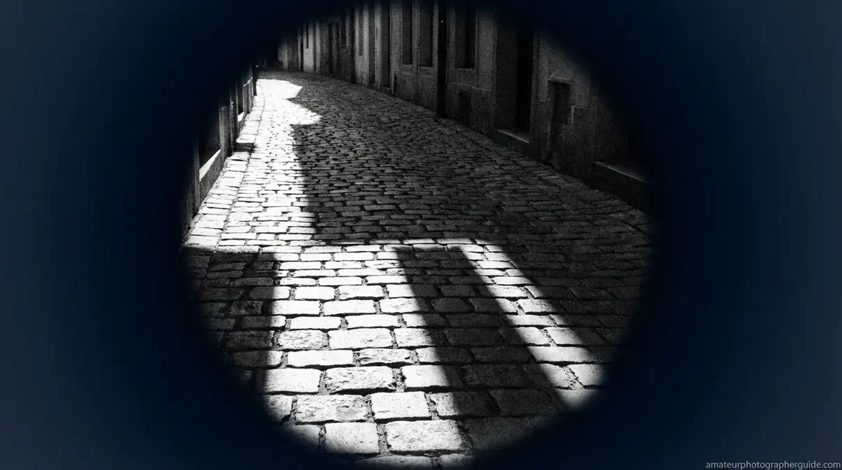 Photographer training eye to see in monochrome by focusing on light, shadow, and texture in cobblestone alley