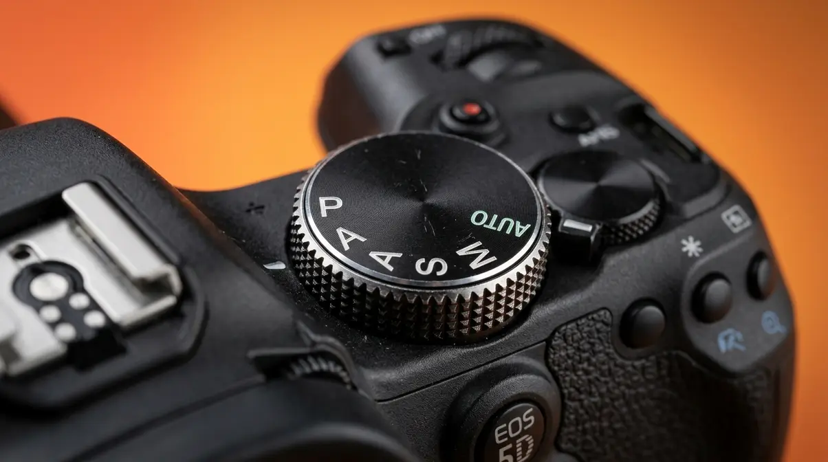 Close-up of camera mode dial showing P A S M Auto positions on DSLR top plate