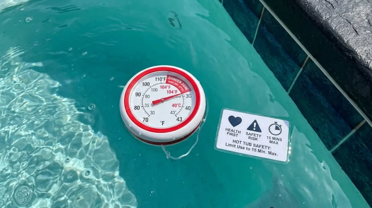 Hot tub thermometer showing 104°F maximum safe temperature limit with health safety reminder card