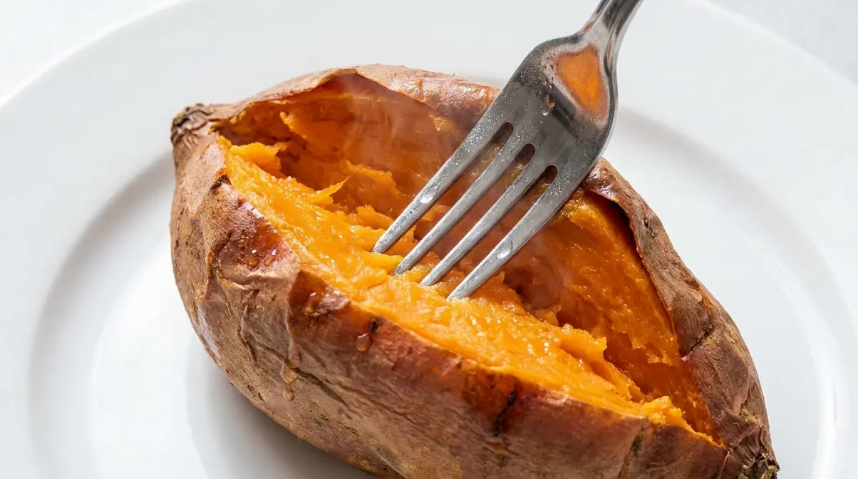How Long To Cook Sweet Potato In Microwave (By Wattage) 7 Fork inserted into center of cooked sweet potato showing fork-tender doneness test