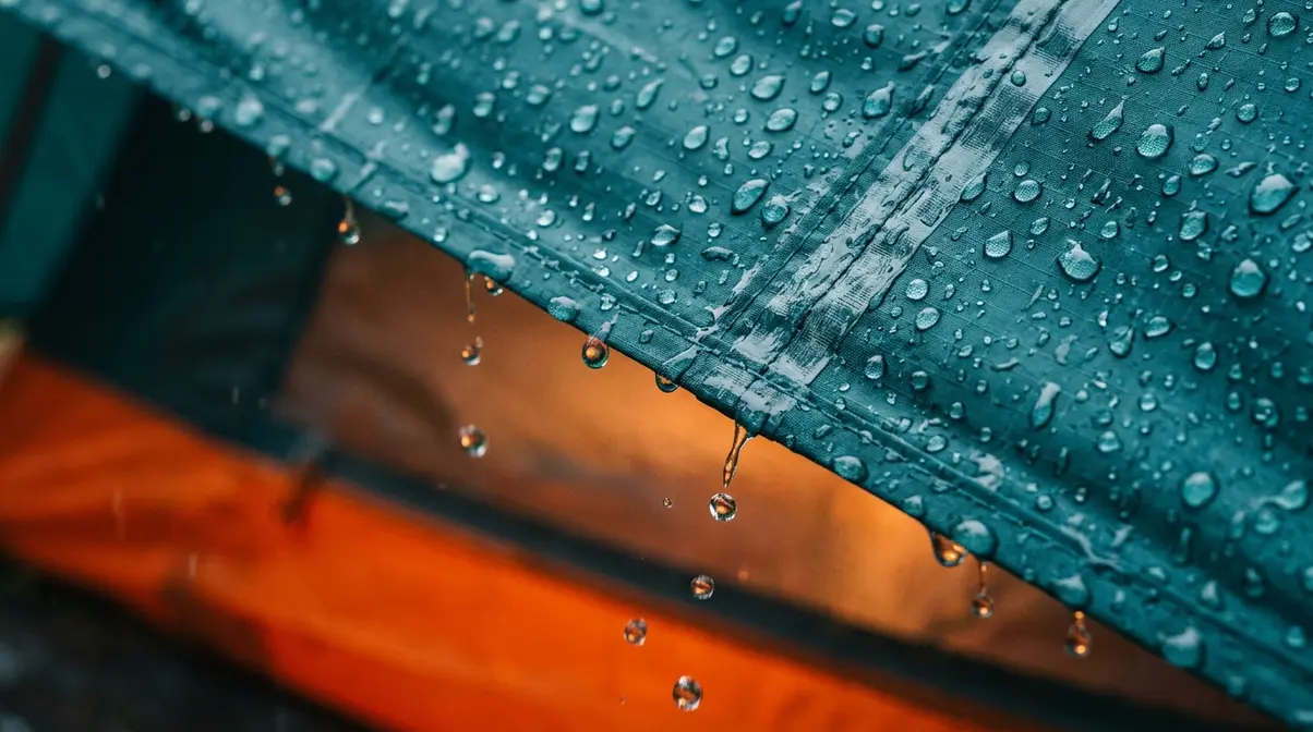 Close-up of tent rainfly fabric with water beading off DWR coating and taped seams visible for waterproofing