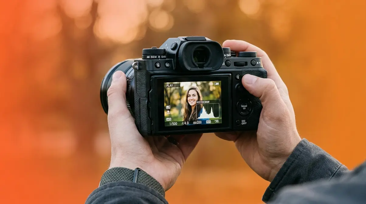 Photographer fixing exposure problems by reviewing histogram on camera LCD screen outdoors