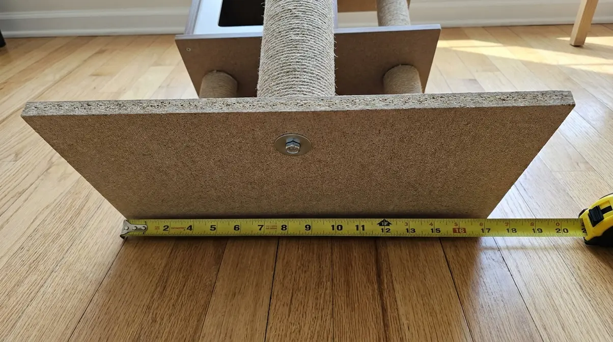 Close-up of Yaheetech cat tree base plate on hardwood floor showing base dimensions and bolt hardware attachment